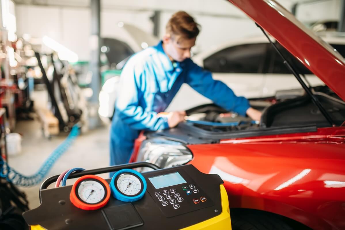 Mechanik przeprowadza naprawę klimatyzacji samochodowych przy użyciu specjalistycznego sprzętu.
