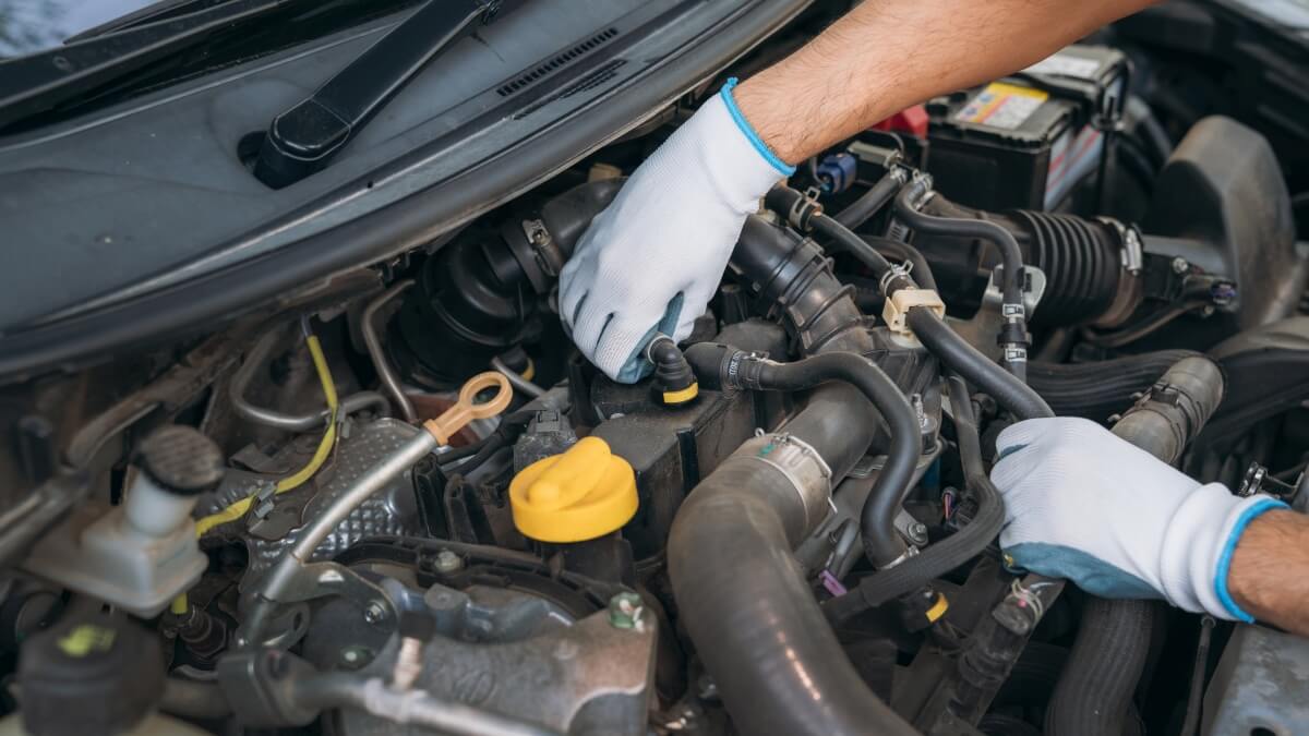 Mechanik w rękawiczkach przeprowadza naprawę silników w samochodzie.
