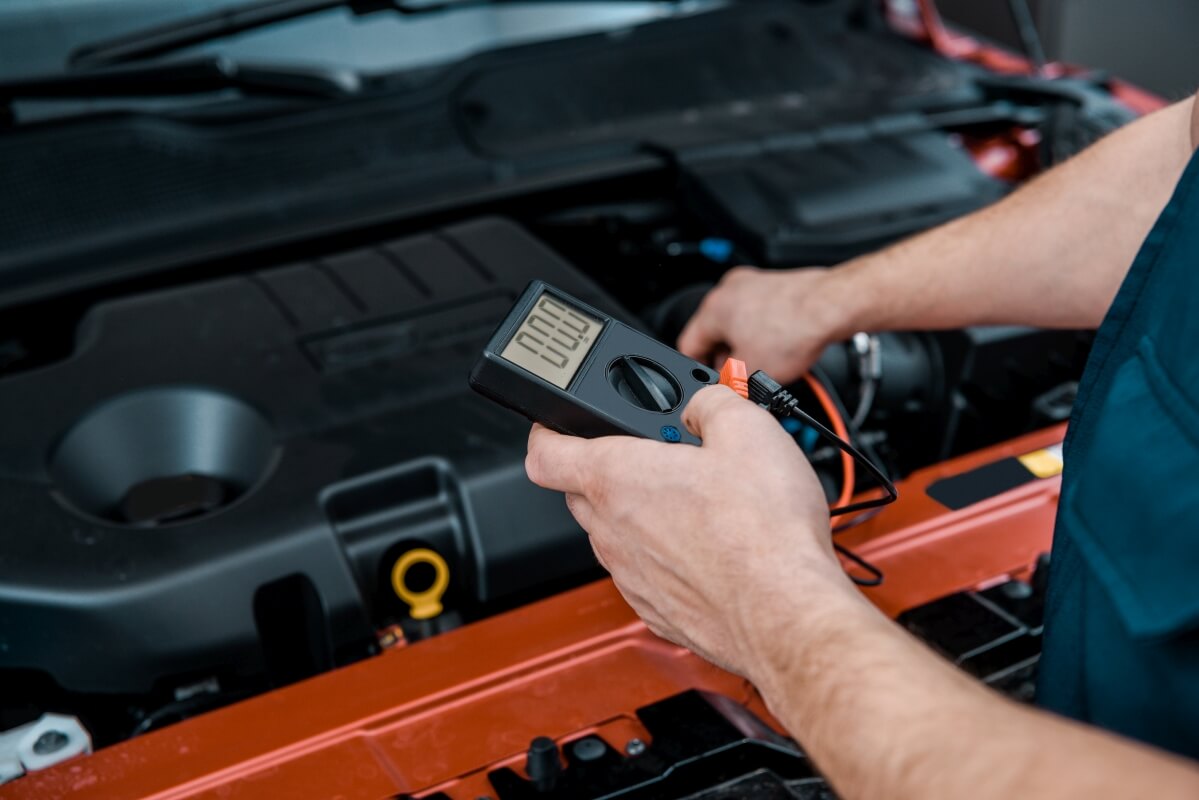 Mechanik przeprowadza diagnostykę silnika za pomocą multimetru.