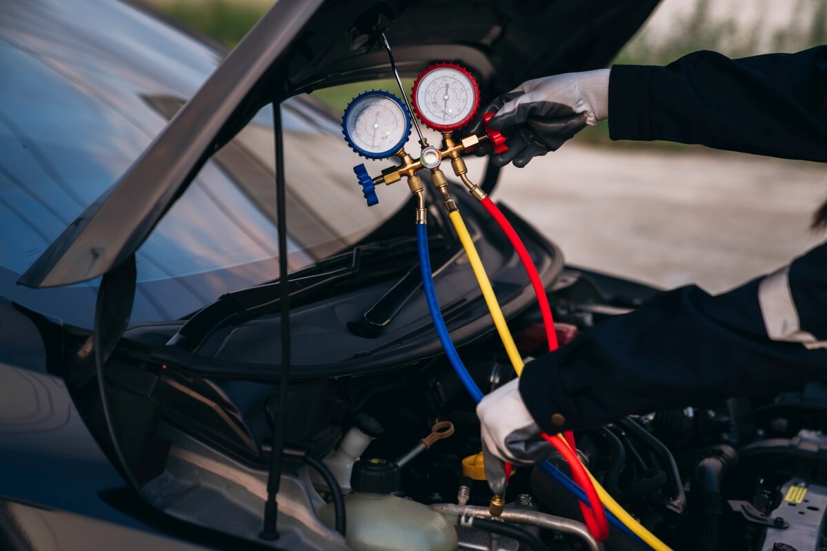 Mechanik dokonuje pomiarów przy naprawie klimatyzacji samochodowych.