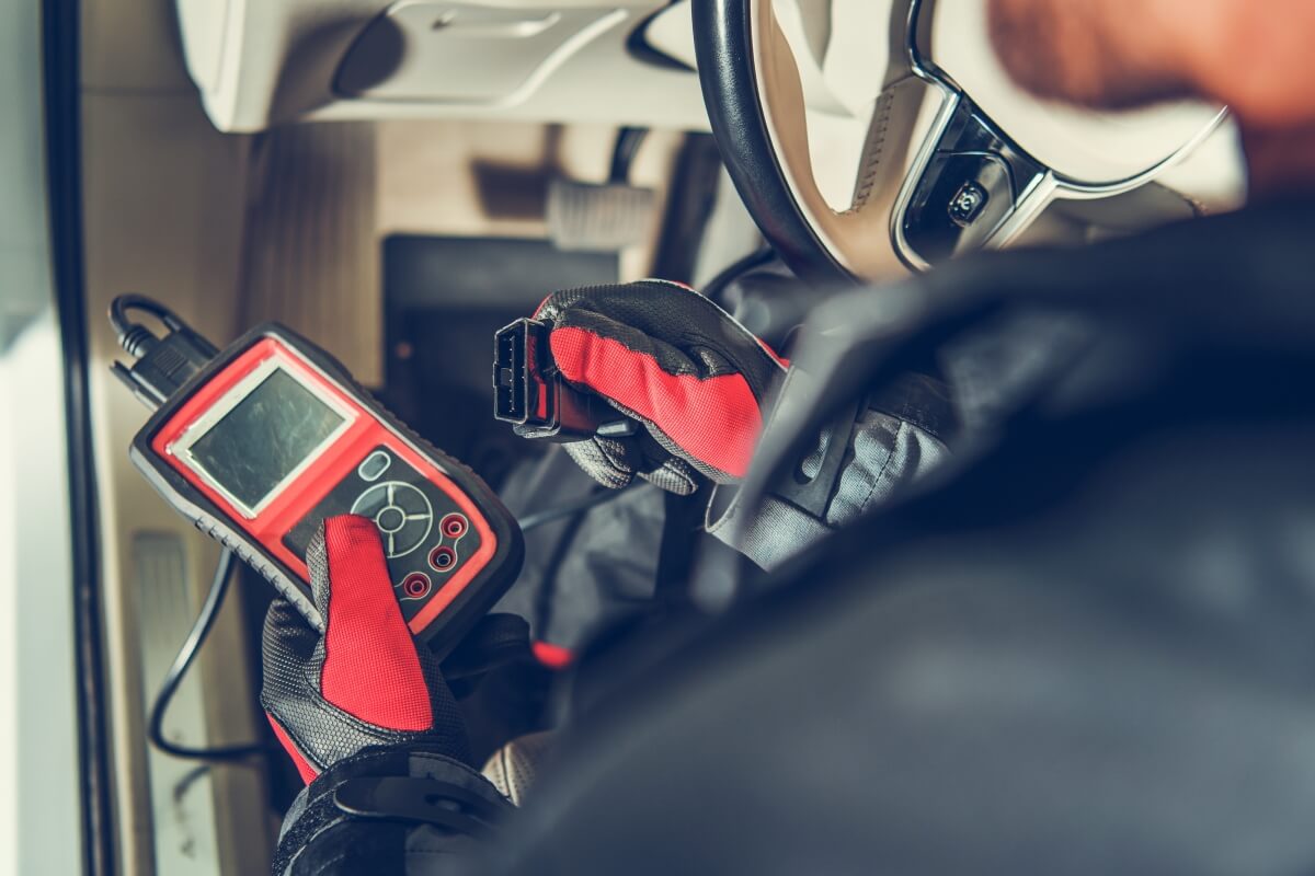 Technik przeprowadza diagnostykę silnika za pomocą urządzenia diagnostycznego.