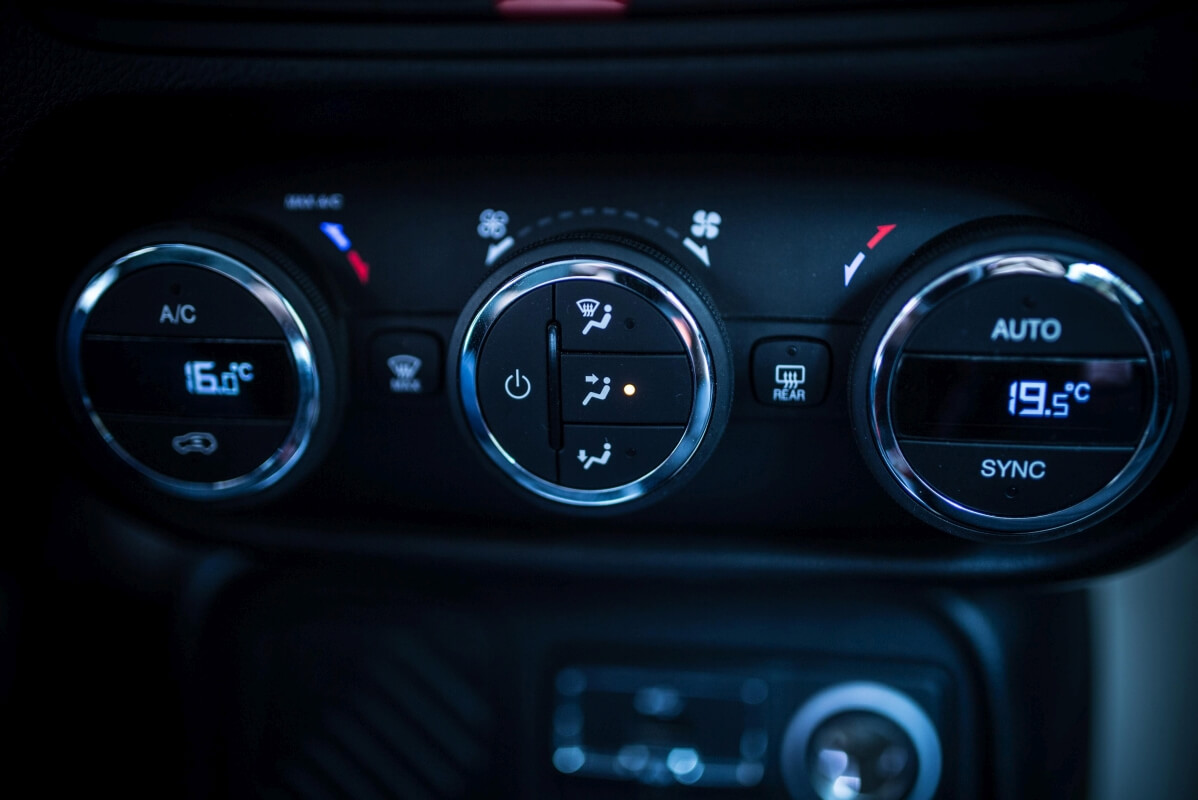 Panel sterowania klimatyzacją w samochodzie, pokazujący potrzebę naprawy klimatyzacji.