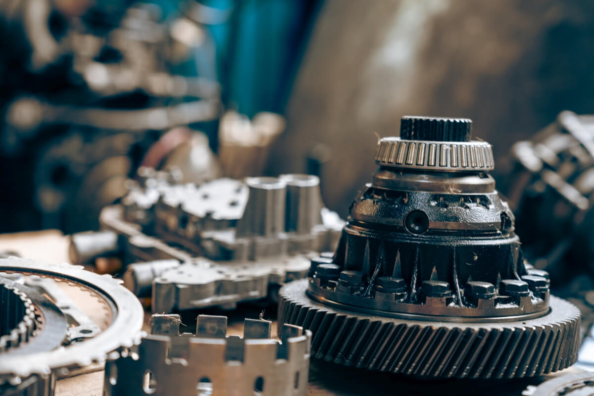 Części mechaniczne na stole warsztatowym, przygotowane do naprawy skrzyni biegów.